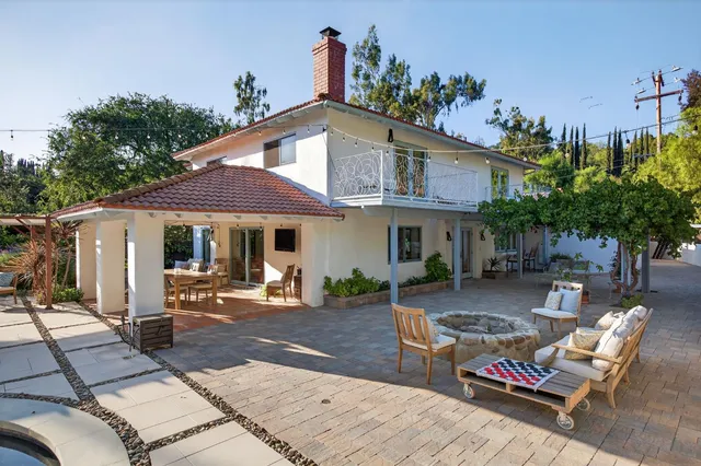 a backyard of a house with table and chairs under an umbrella
