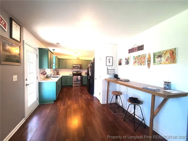 a view of a kitchen with kitchen island wooden floors and stainless steel appliances