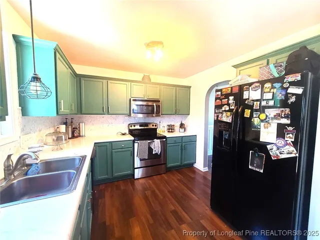 a kitchen with stainless steel appliances granite countertop a refrigerator a sink dishwasher and a stove with wooden floor