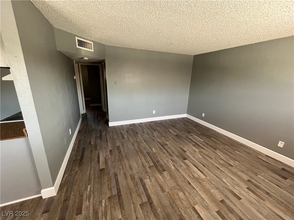 Spare room featuring dark wood-type flooring and a textured ceiling