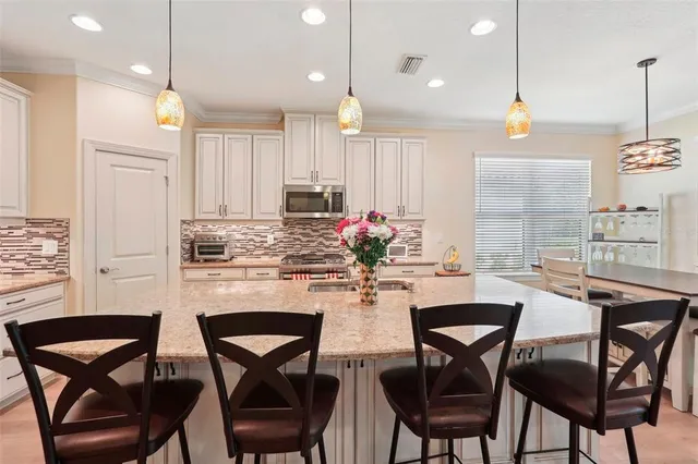 a kitchen with stainless steel appliances granite countertop a stove top oven a sink dining table and chairs with white cabinets