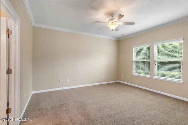 an empty room with chandelier fan and windows
