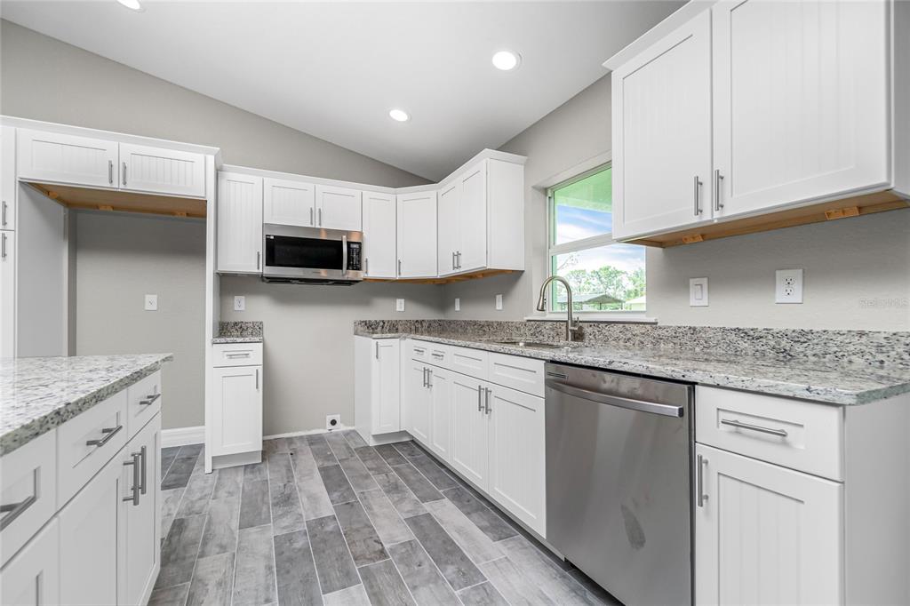 6 Cockpit Lane Placida, FL 33946 - Photo 6 of 20 a kitchen with granite countertop a sink dishwasher a stove and a microwave oven with cabinets