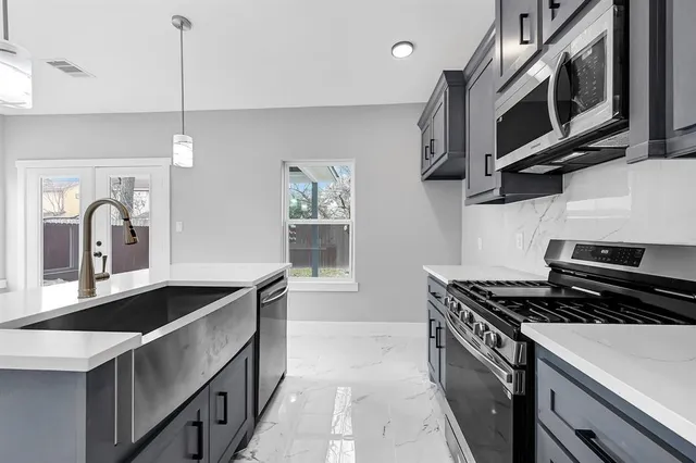 a kitchen with stainless steel appliances granite countertop a sink stove and microwave