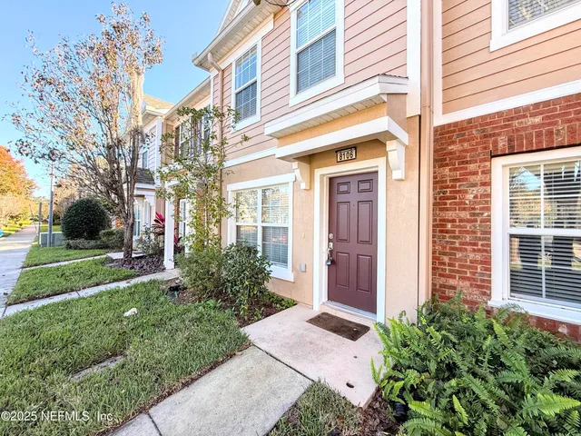a view of a brick house with a yard potted plants