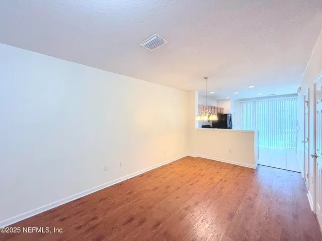 a view of kitchen and empty room with wooden floor
