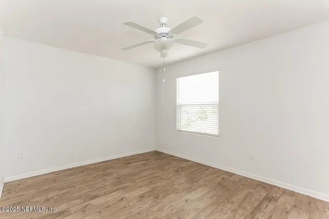 an empty room with wooden floor and ceiling fan