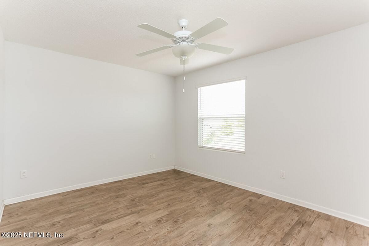 514 Eiseman Way Jacksonville, FL 32216 - Photo 8 of 15 an empty room with wooden floor and ceiling fan