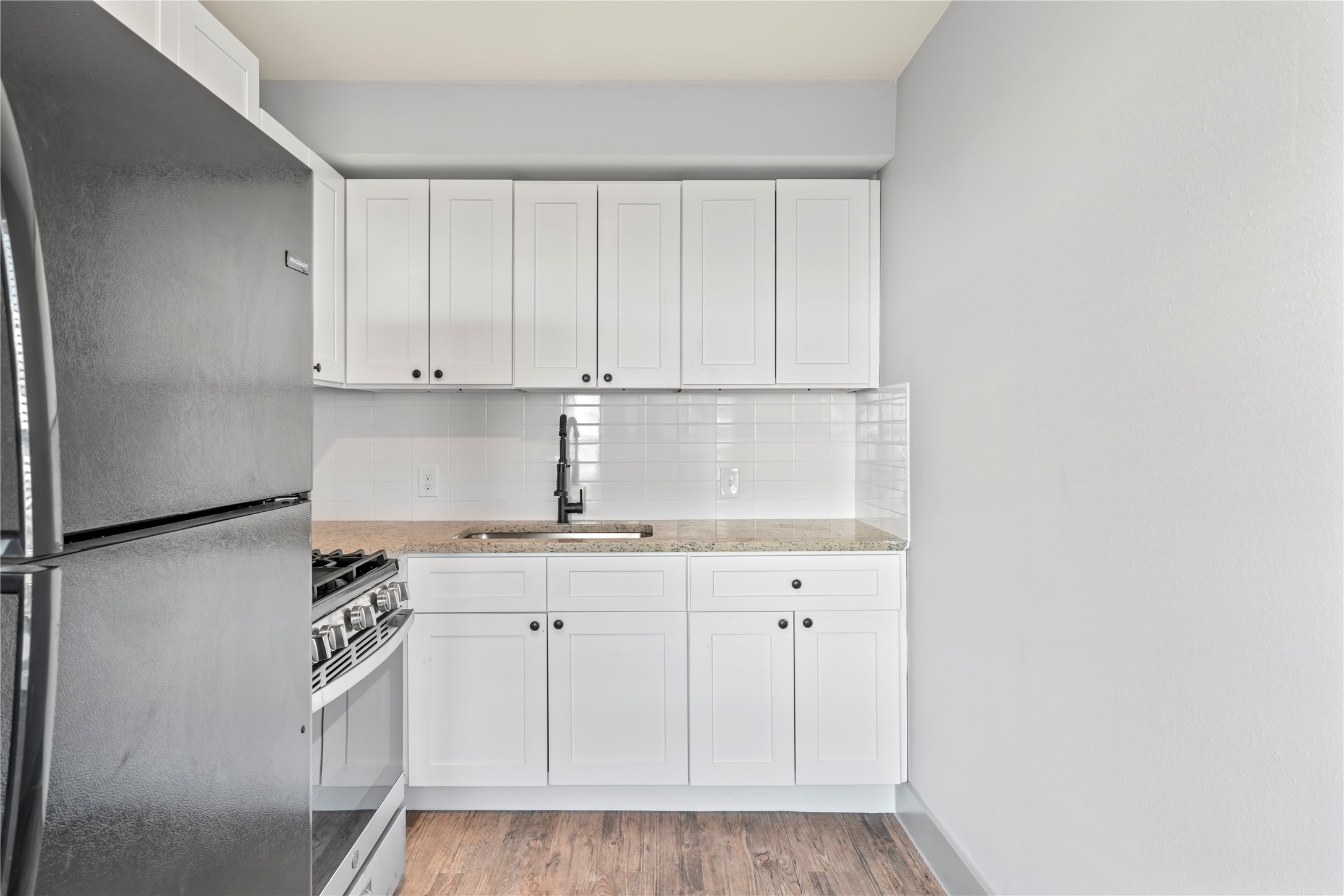305 Roberts Street, Unit 10 Houston, TX 77003 - Photo 3 of 7 a kitchen with granite countertop white cabinets and white appliances