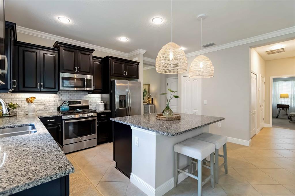 12252 Stuart Drive Venice, FL 34293 - Photo 15 of 70 a kitchen with stainless steel appliances granite countertop a stove top oven a sink dishwasher a dining table and chairs