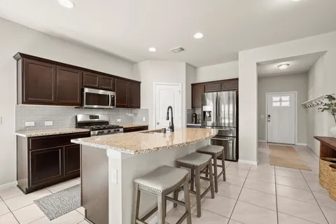 a kitchen with stainless steel appliances granite countertop a stove top oven a sink dishwasher a dining table and chairs