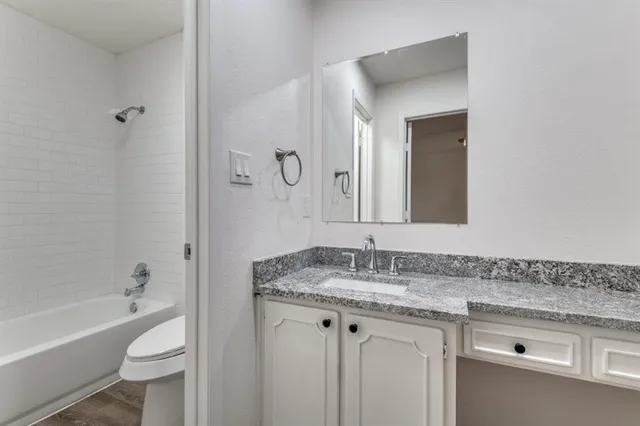 a bathroom with a granite countertop sink toilet and shower