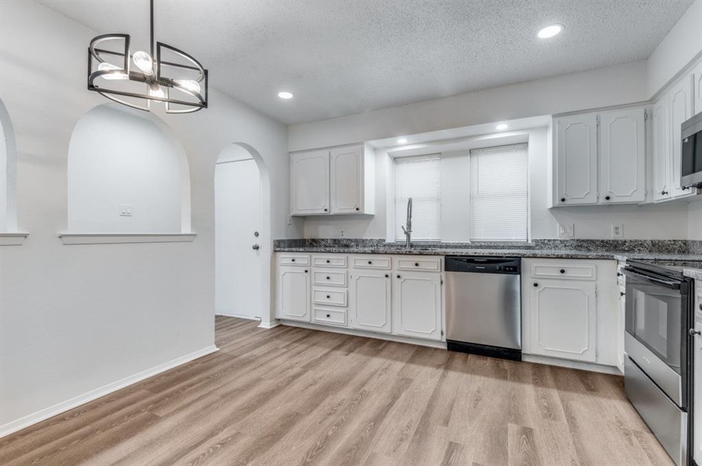2308 West Oakdale Road Irving, TX 75060 - Photo 4 of 12 a kitchen with granite countertop white cabinets and stainless steel appliances