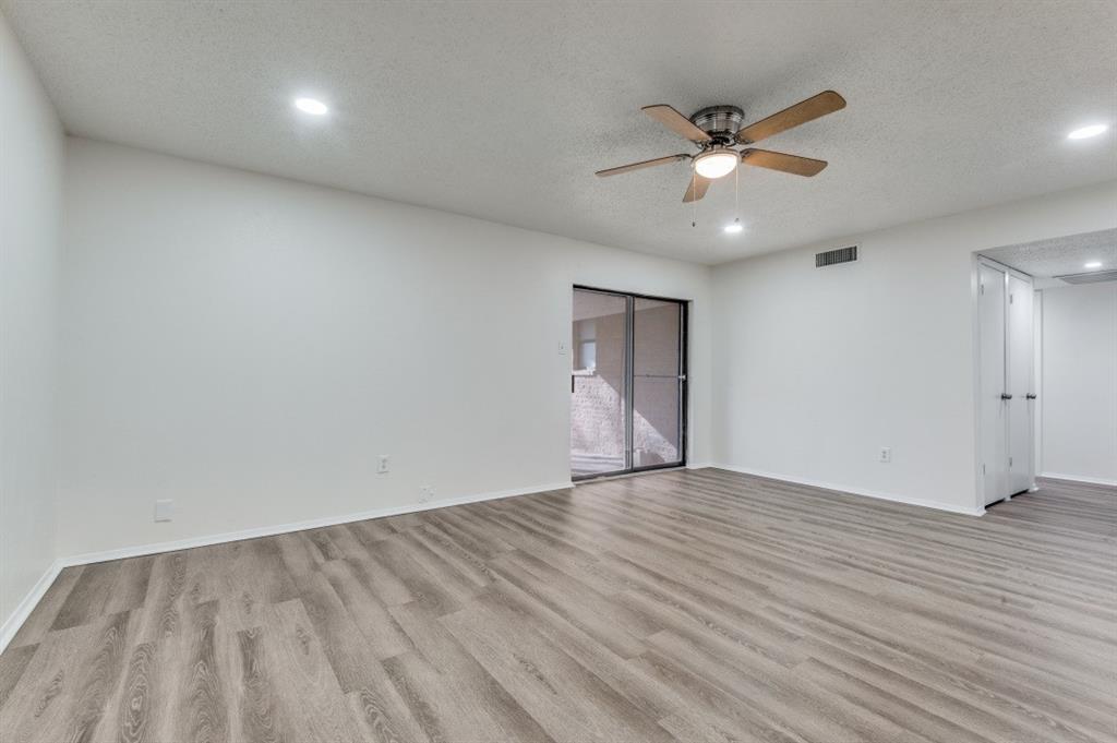 2308 West Oakdale Road Irving, TX 75060 - Photo 6 of 12 an empty room with wooden floor chandelier fan and windows