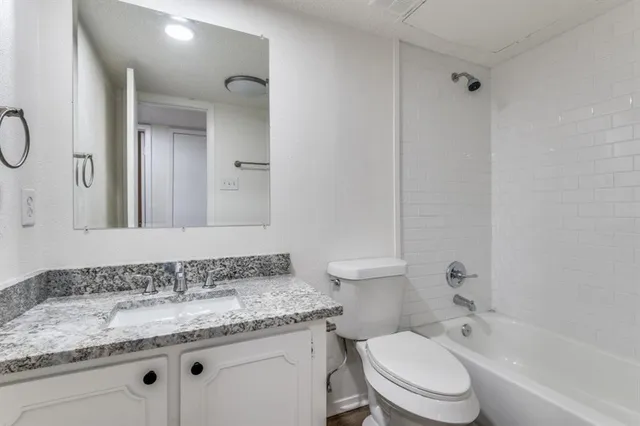 a bathroom with a granite countertop toilet sink and mirror