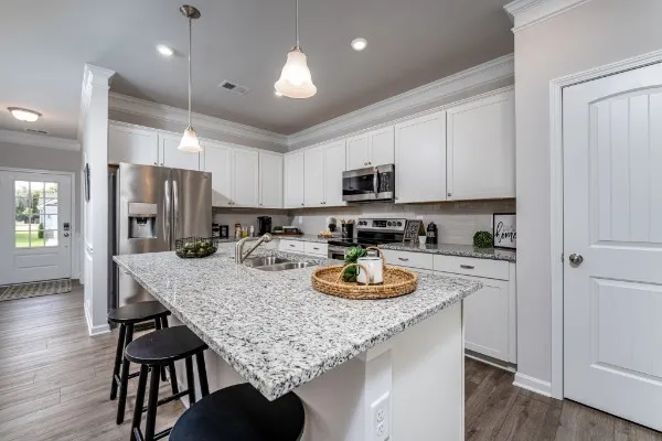 a kitchen with stainless steel appliances kitchen island granite countertop a stove a microwave and a sink with granite countertops