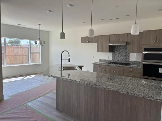 a kitchen with kitchen island granite countertop a sink appliances and cabinets