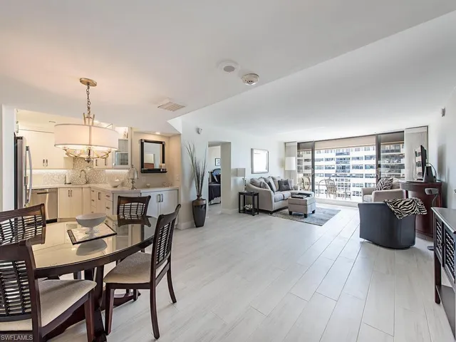 a living room with furniture kitchen view and a wooden floor