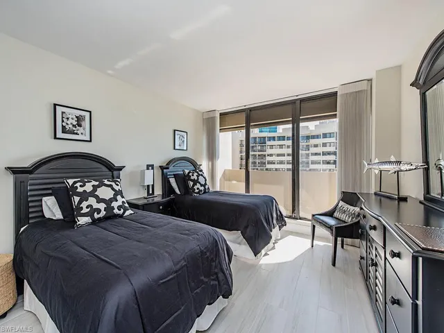 a bedroom with a bed a couch and a large window with wooden floor