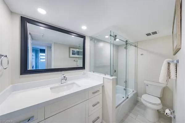 a bathroom with a sink a toilet a mirror and shower