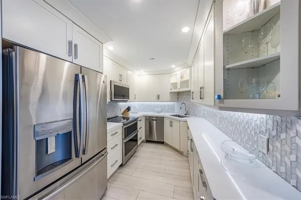 a large kitchen with a sink stainless steel appliances and cabinets