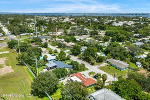 an aerial view of residential houses with outdoor space and trees
