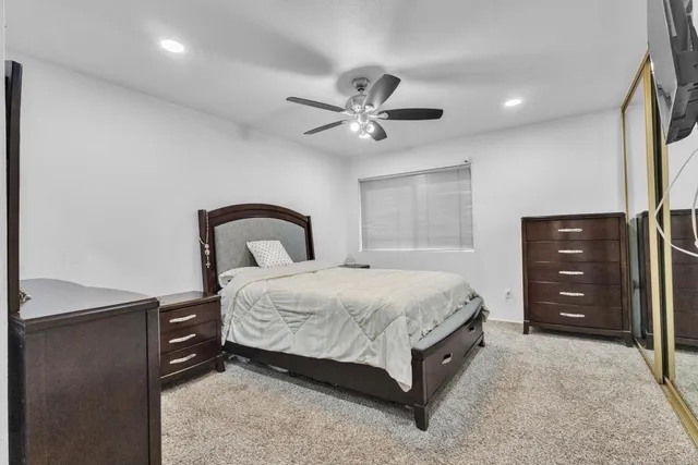 a large bedroom with a bed and a flat tv screen on dresser