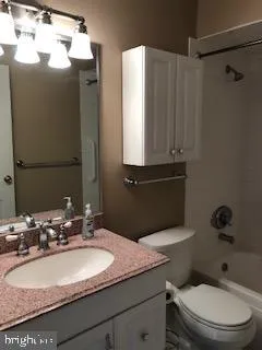 a bathroom with a granite countertop sink toilet and mirror