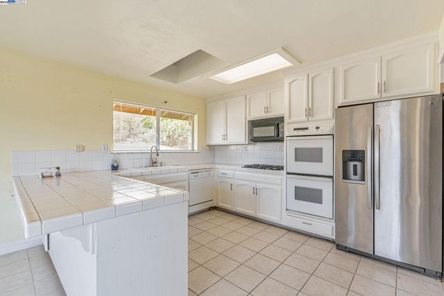 a kitchen with white cabinets and white appliances