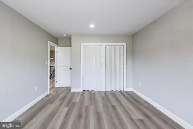 a view of a hallway with wooden floor and a bathroom