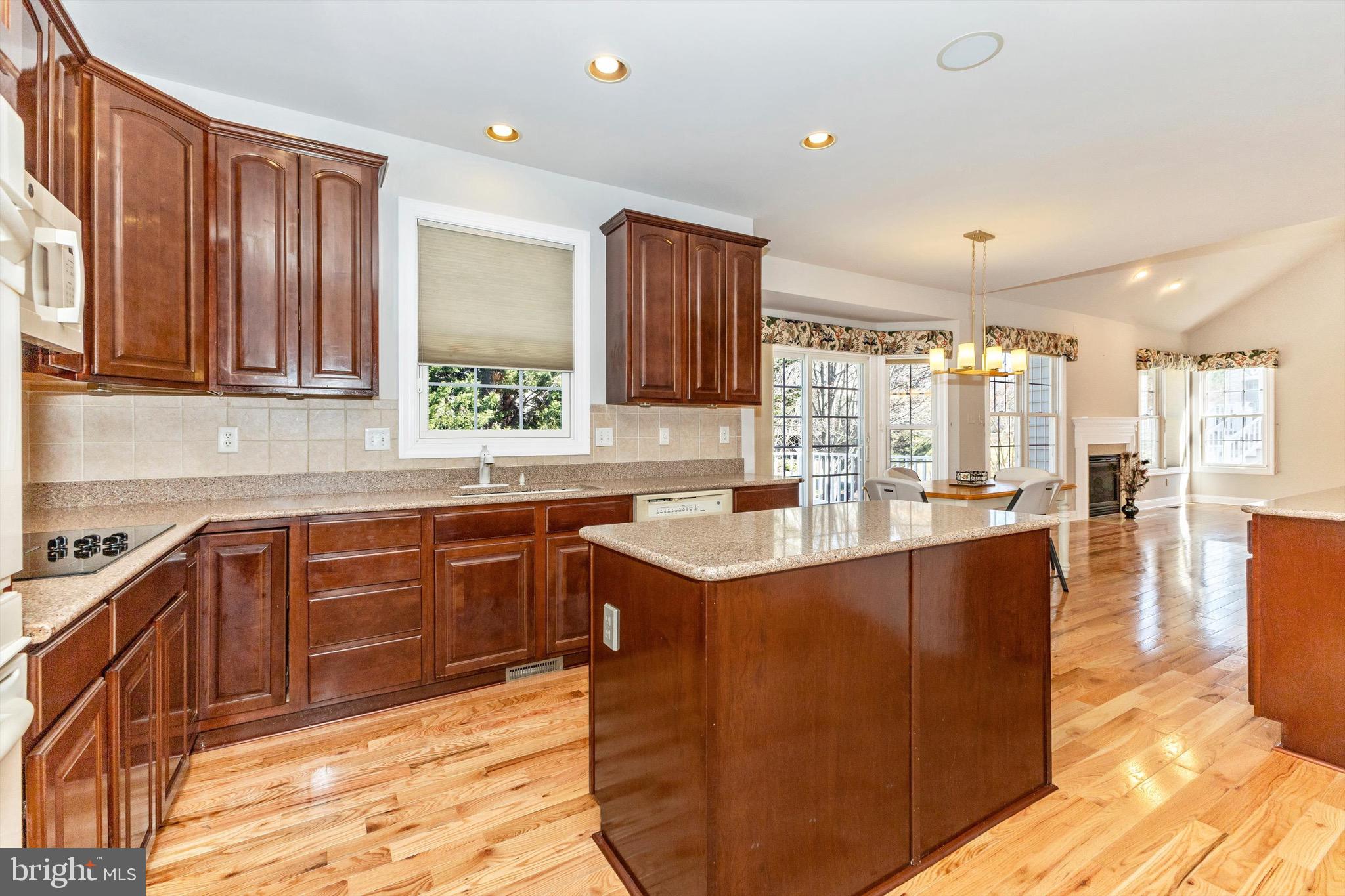 10213 Deep Skies Drive Laurel, MD 20723 - Photo 19 of 56 a large kitchen with kitchen island granite countertop a sink and dishwasher wooden cabinets with granite countertops