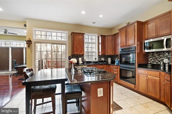 a kitchen with stainless steel appliances a refrigerator a stove top oven and a dining table with wooden floor
