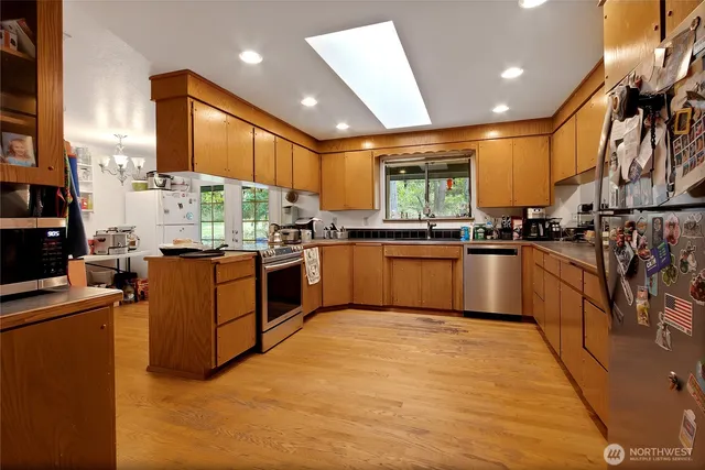 a kitchen with stainless steel appliances granite countertop wooden cabinets a sink dishwasher a stove and a refrigerator