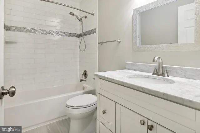 a bathroom with a granite countertop sink a toilet and shower