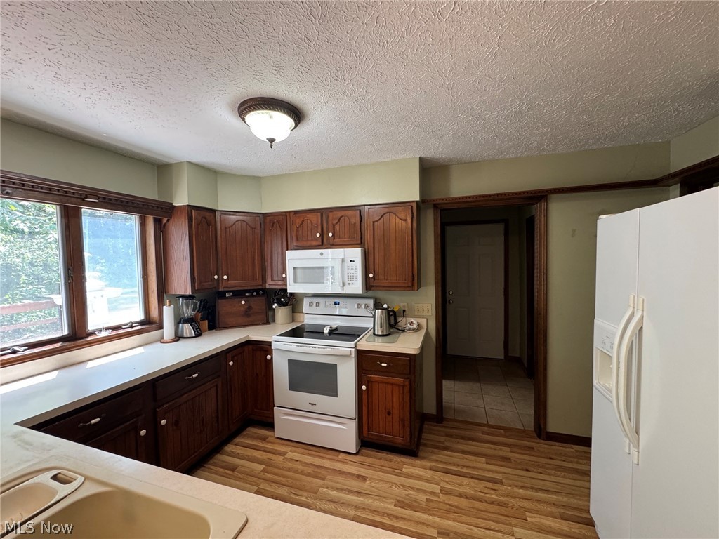 8201 Orchard Road Painesville, OH 44077 - Photo 8 of 45 Kitchen featuring wood-finish flooring, wood cabinetry, light countertops, and an integrated white appliance package