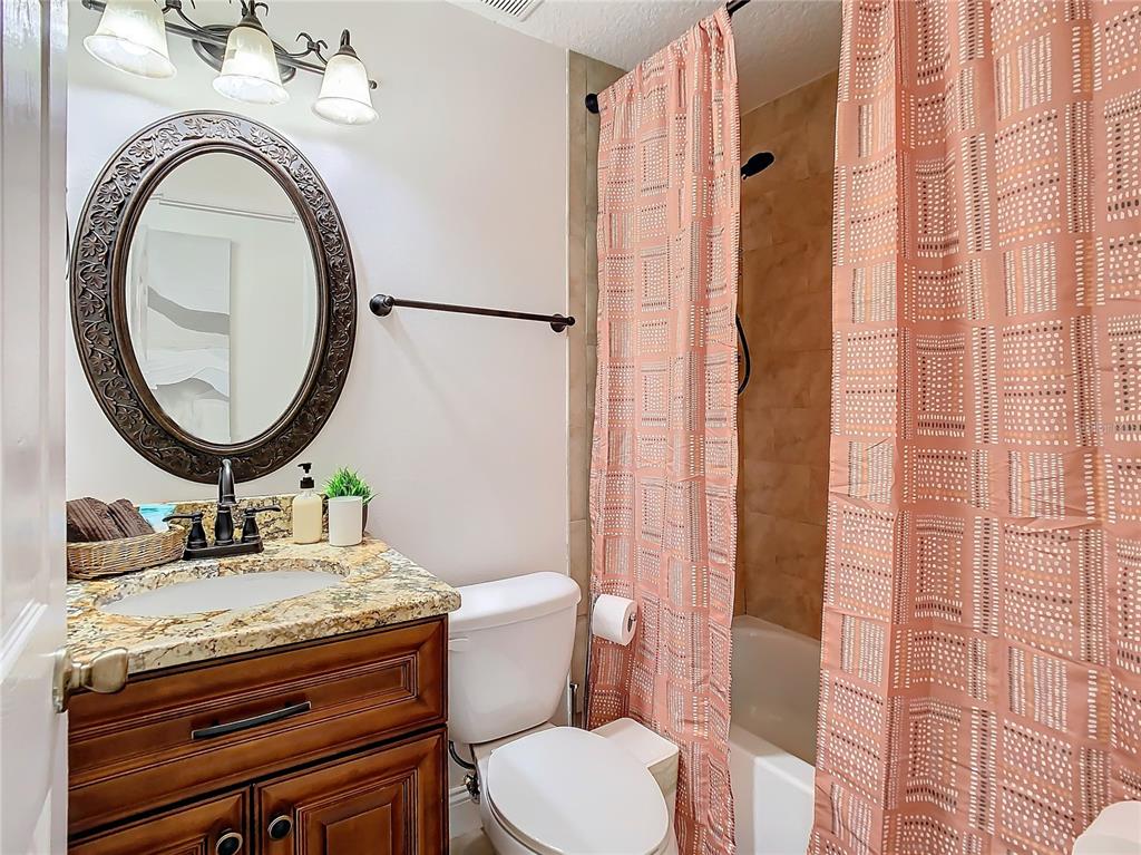 2907 West Arch Street Tampa, FL 33607 - Photo 28 of 48 a bathroom with a granite countertop toilet a sink and a mirror