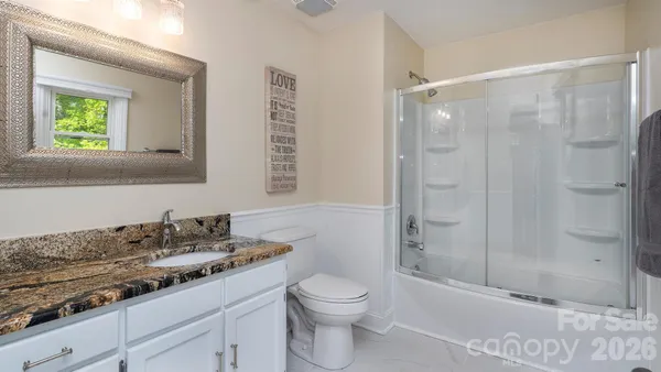 a bathroom with a granite countertop sink a toilet and shower