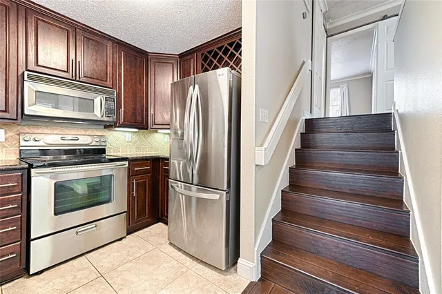 a kitchen with granite countertop stainless steel appliances a stove top oven and cabinets