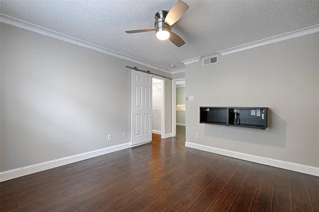 a view of an empty room with wooden floor and a ceiling fan