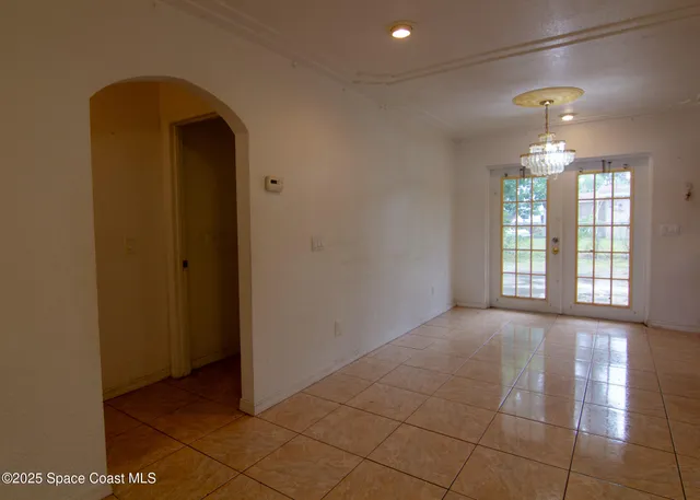a view of an empty room with chandelier fan and fire place