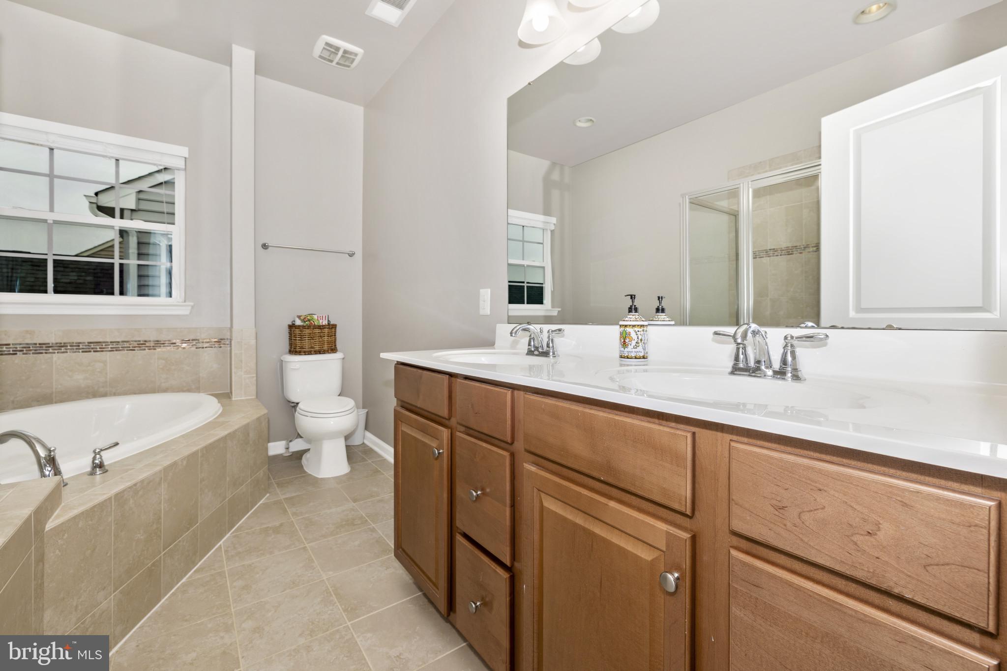 1912 Regiment Way Frederick, MD 21702 - Photo 26 of 45 a bathroom with a double vanity sink a large mirror and a bathtub
