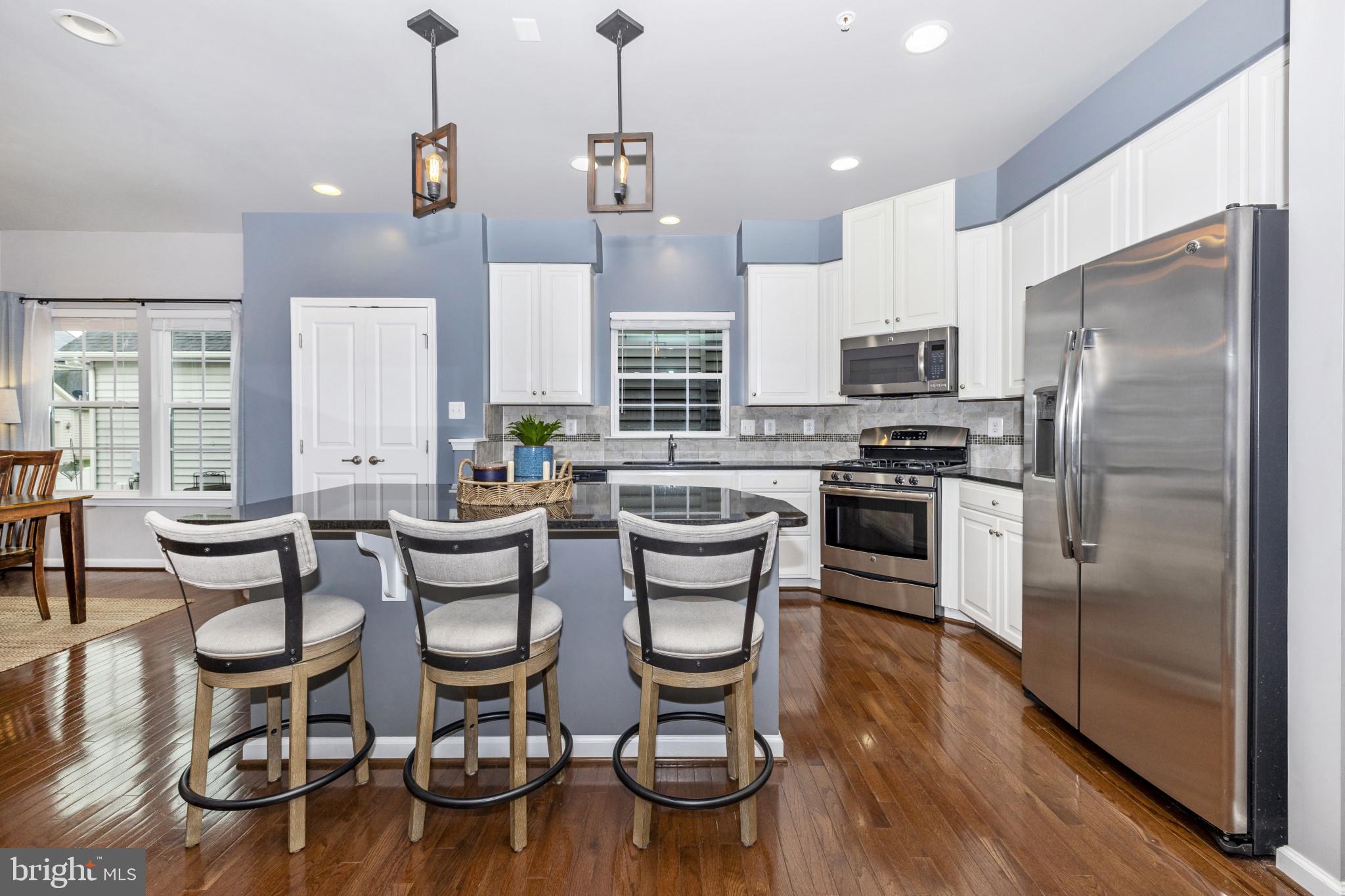 1912 Regiment Way Frederick, MD 21702 - Photo 9 of 45 a kitchen with stainless steel appliances kitchen island granite countertop a table chairs stove and refrigerator