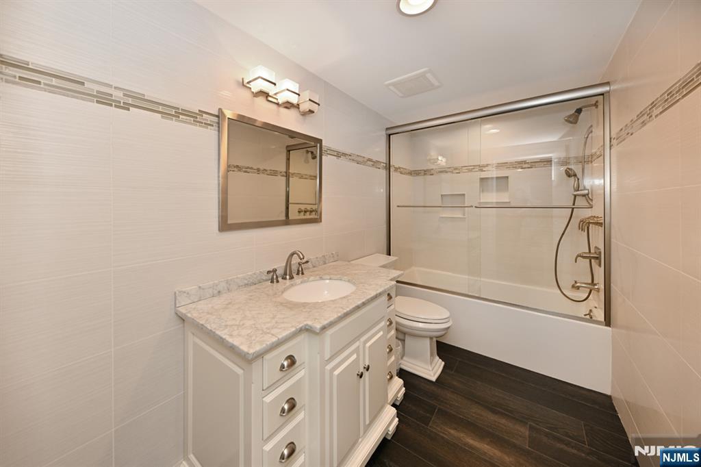 40 Plymouth Road Hillsdale, NJ 07642 - Photo 23 of 33 a bathroom with a granite countertop sink a toilet a mirror a vanity and shower