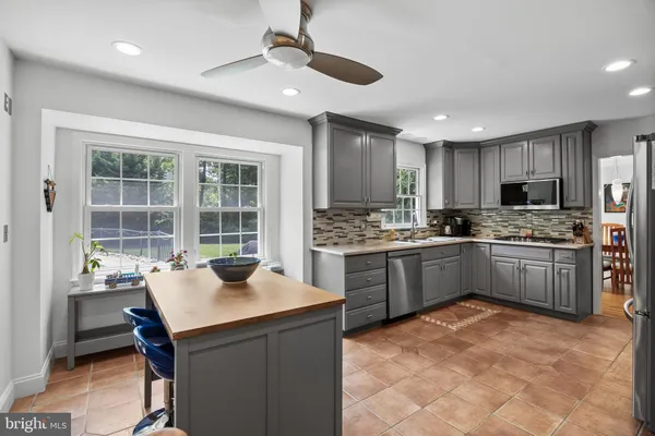 a kitchen with a refrigerator a stove a sink dishwasher with a dining table and chair with wooden floor