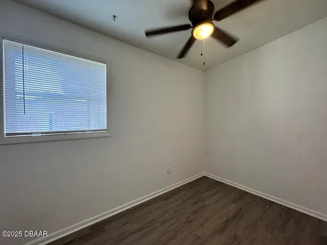 an empty room with a window and a chandelier fan