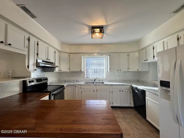 a kitchen with stainless steel appliances granite countertop a refrigerator a sink dishwasher a stove and white countertops with wooden floor