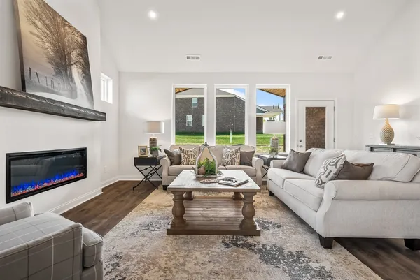 a living room with furniture a rug a fireplace and a window