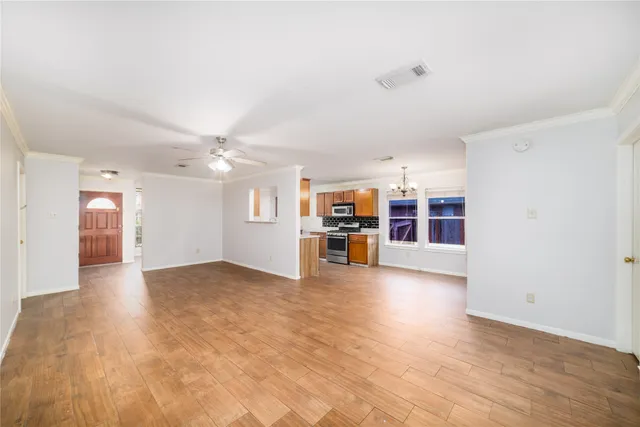 a view of a big room with wooden floor and windows