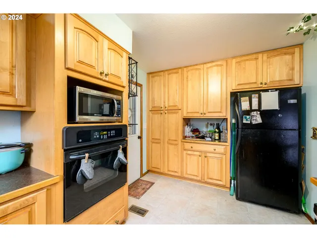 a kitchen with stainless steel appliances granite countertop a refrigerator a stove and a sink with large cabinets