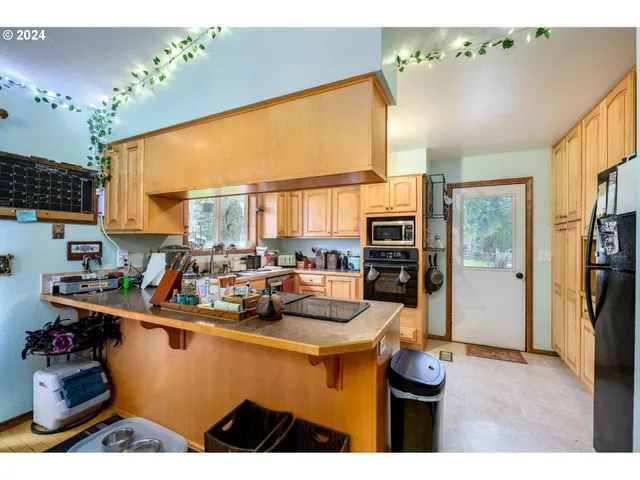 a room with stainless steel appliances a dining table wooden floor and a large window